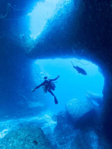 宮古島L字アーチでロウニンアジと並んで泳ぐダイビングガイド竹内。ワイド撮影の絶景