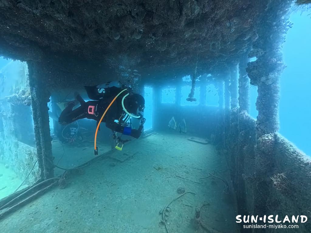 沈船の狭い操舵室の窓を中性浮力で通り抜けるダイバー。高度な浮力コントロール