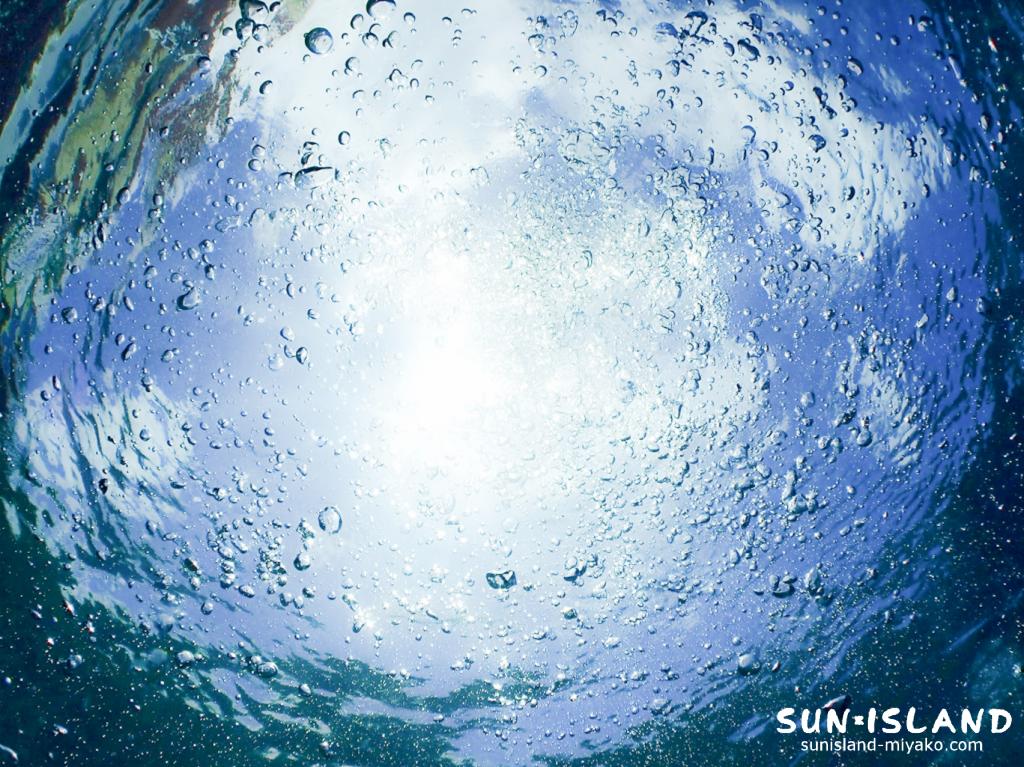 抜群の透明度を誇る4月の宮古島で光を反射して輝くダイバーの排気泡