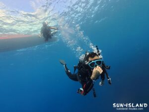 澄んだ水中で、ダイバーがダイブコンピューターをしっかり見つめているダイバー